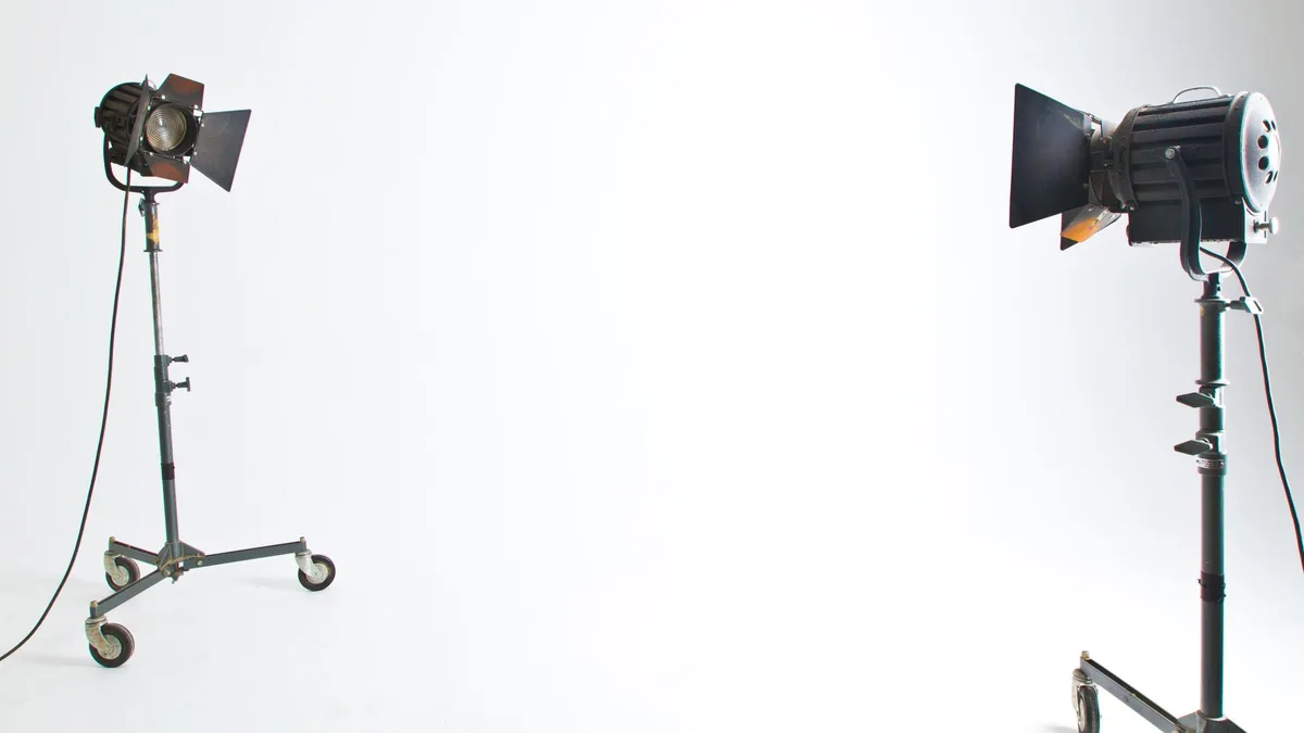 Two studio lights facing an empty white backdrop in a small product photography studio
