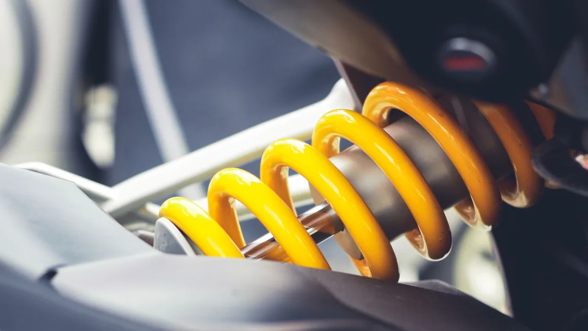 Close-up of a tightly wound yellow metal coil spring under compression