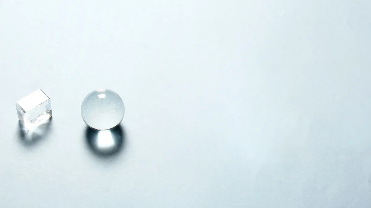 A transparent crystal sphere and cube casting soft shadows on a pale surface